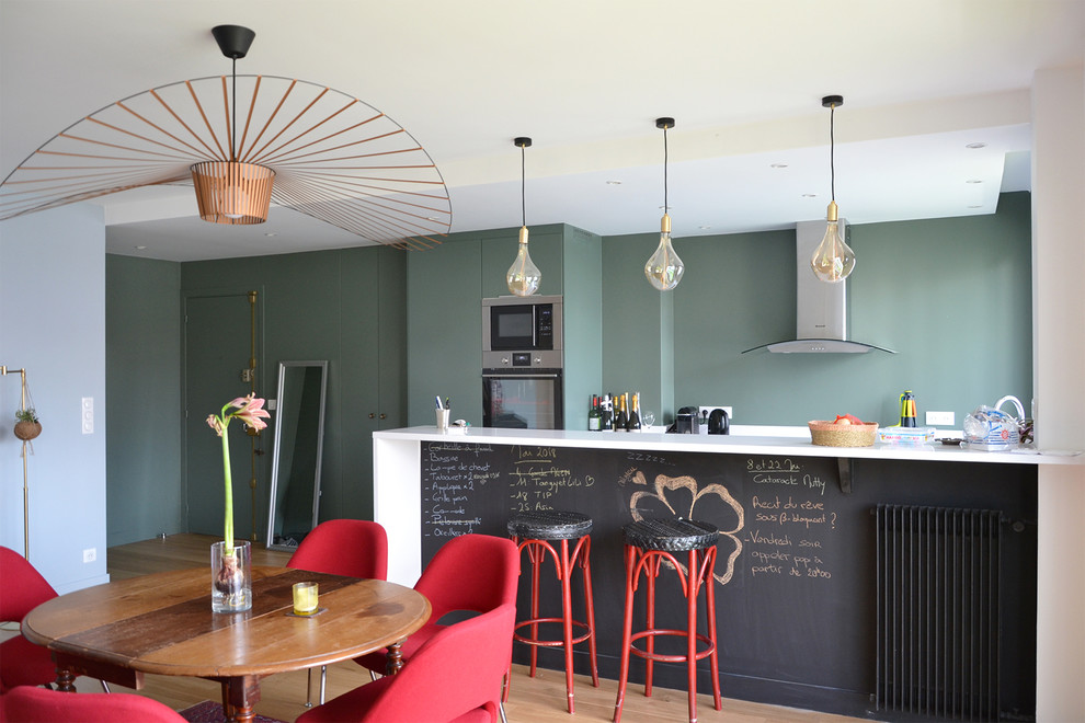 パリにあるコンテンポラリースタイルのおしゃれなキッチン (フラットパネル扉のキャビネット、緑のキャビネット、珪岩カウンター、シルバーの調理設備、淡色無垢フローリング、ベージュの床、白いキッチンカウンター) の写真