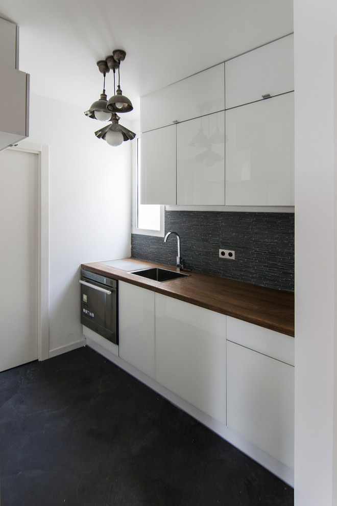 Esempio di una piccola cucina lineare contemporanea chiusa con lavello da incasso, ante bianche, top in legno, paraspruzzi nero e elettrodomestici da incasso