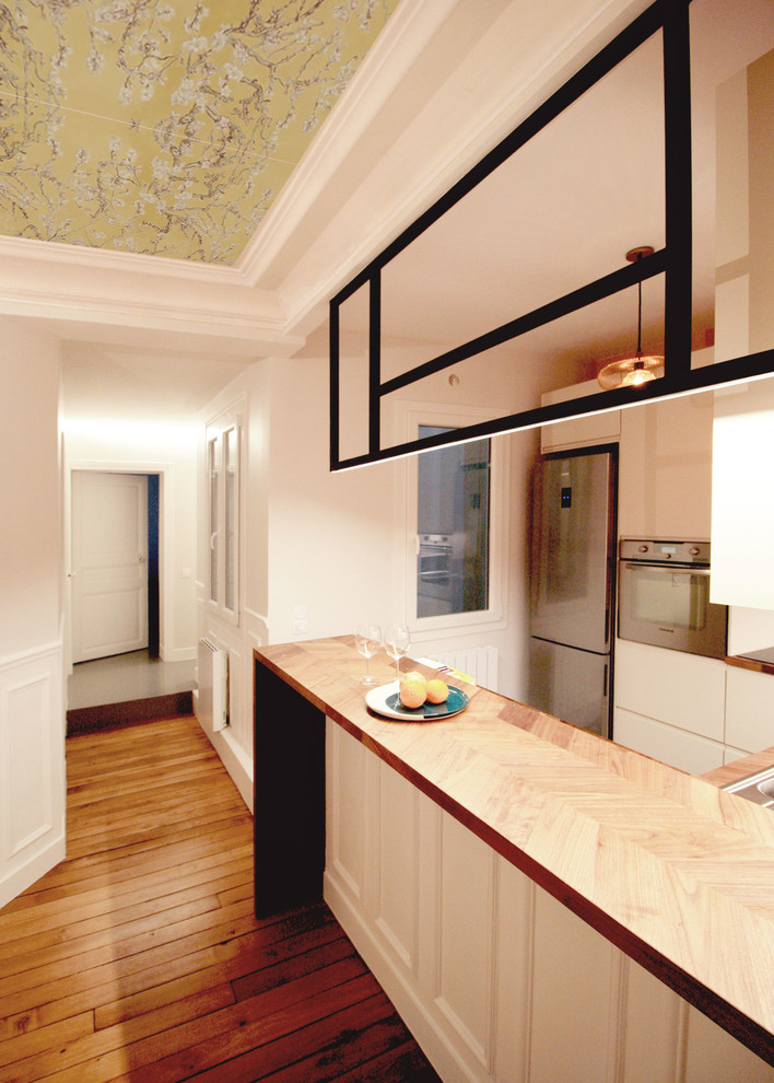 Bild på ett mellanstort funkis kök, med en undermonterad diskho, beige skåp, träbänkskiva, brunt stänkskydd, stänkskydd i trä, rostfria vitvaror, cementgolv, en köksö och turkost golv