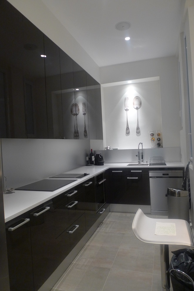 Foto di una piccola cucina design con lavello sottopiano, ante bianche, top bianco, elettrodomestici in acciaio inossidabile, parquet chiaro, pavimento marrone e ante a filo
