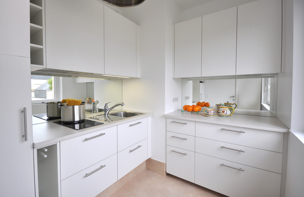 Kleine Moderne Küche in L-Form mit integriertem Waschbecken, flächenbündigen Schrankfronten, weißen Schränken und Rückwand aus Spiegelfliesen in Paris