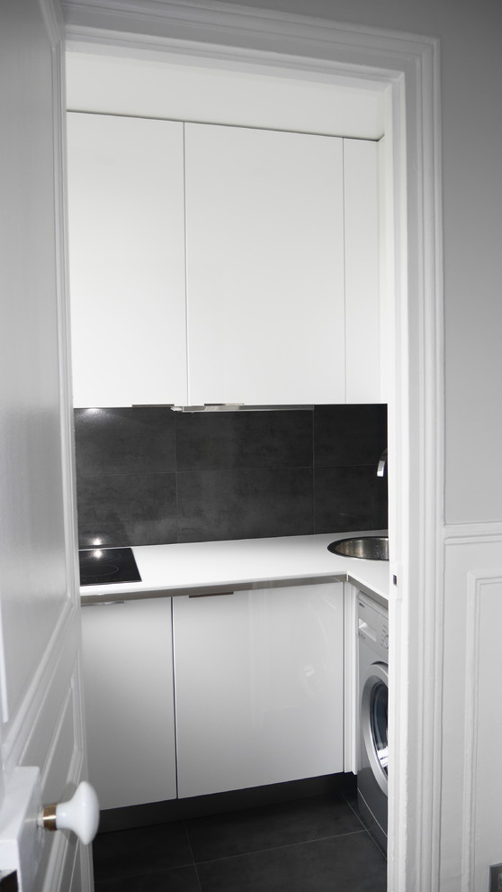 Idée de décoration pour une cuisine minimaliste en U fermée et de taille moyenne avec un évier intégré, une crédence noire et un sol noir.