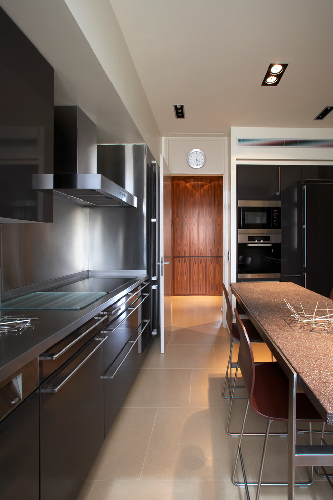 Bild på ett stort funkis linjärt kök och matrum, med släta luckor, svarta skåp, stänkskydd med metallisk yta, svarta vitvaror och en köksö