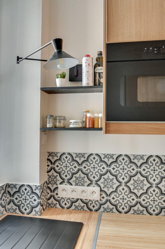 Design ideas for a small classic l-shaped enclosed kitchen in Paris with a built-in sink, flat-panel cabinets, light wood cabinets, wood worktops, grey splashback, cement tile splashback, black appliances, cement flooring, no island and grey floors.
