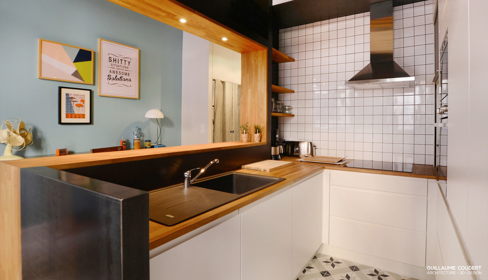 Aménagement d'une cuisine ouverte rétro en U avec des portes de placard blanches, un plan de travail en bois et une crédence en céramique.