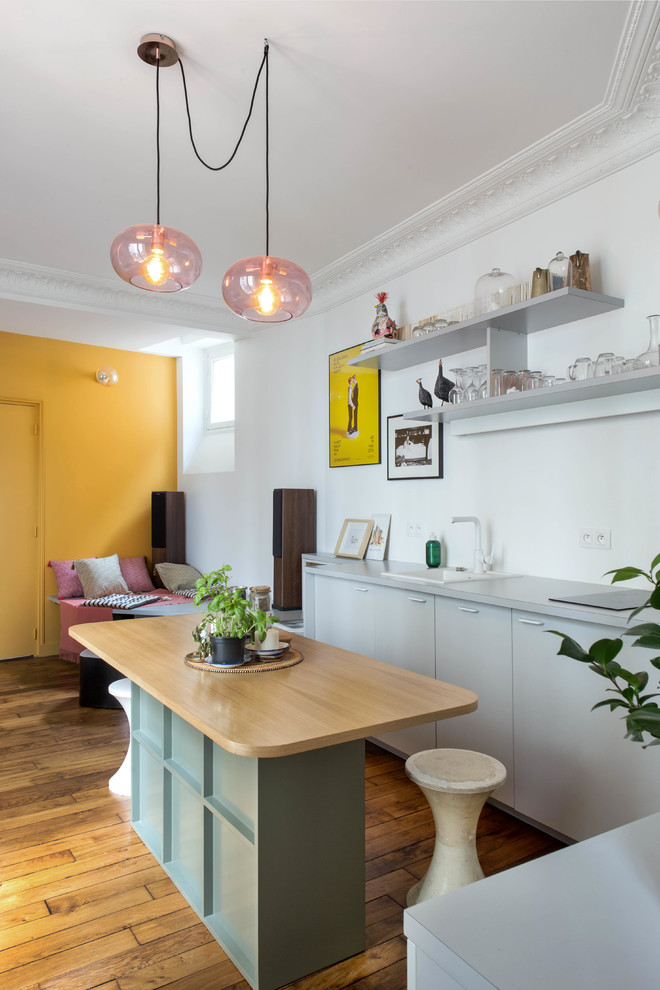Immagine di una piccola cucina nordica con ante lisce, ante grigie, pavimento in legno massello medio, top grigio, elettrodomestici bianchi, pavimento marrone e lavello sottopiano