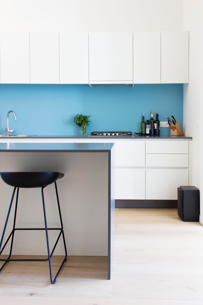 Modelo de cocina moderna con puertas de armario blancas, encimera de laminado, salpicadero azul y una isla