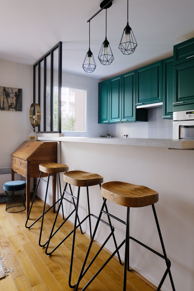 Inspiration för ett mellanstort vintage grå grått kök, med luckor med infälld panel, gröna skåp, laminatbänkskiva, grått stänkskydd, stänkskydd i keramik, cementgolv, en halv köksö och grått golv