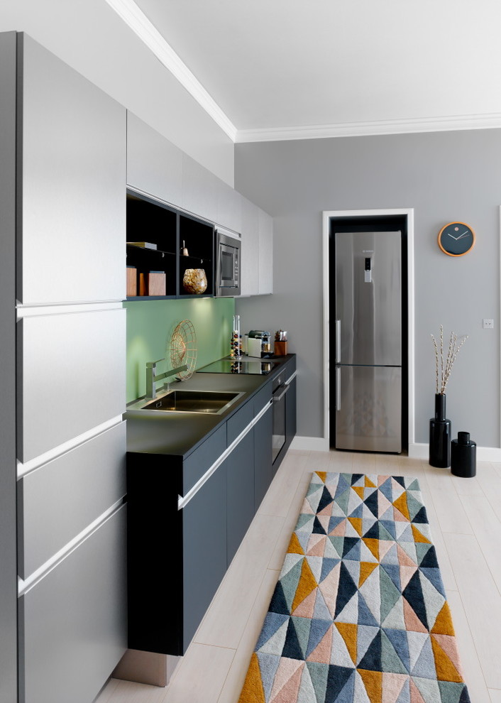 Идея дизайна: прямая кухня-гостиная в современном стиле с серыми фасадами, столешницей из ламината, зеленым фартуком, фартуком из стекла и техникой из нержавеющей стали без острова