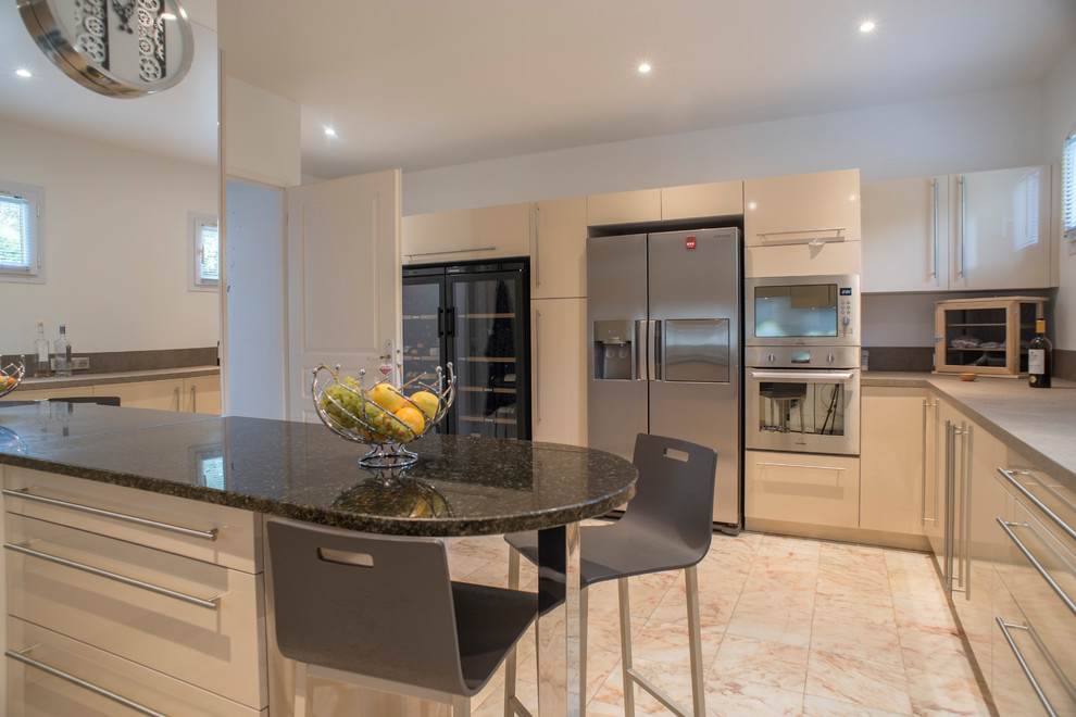 Photo of a large contemporary u-shaped enclosed kitchen in Bordeaux with a submerged sink, flat-panel cabinets, beige cabinets, laminate countertops, beige splashback, stainless steel appliances, marble flooring, a breakfast bar and beige floors.