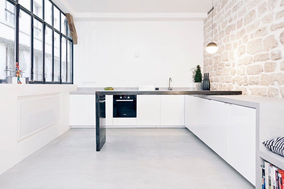 Foto di una piccola cucina industriale con ante lisce, ante bianche, top in acciaio inossidabile, paraspruzzi bianco, pavimento in cemento e nessuna isola