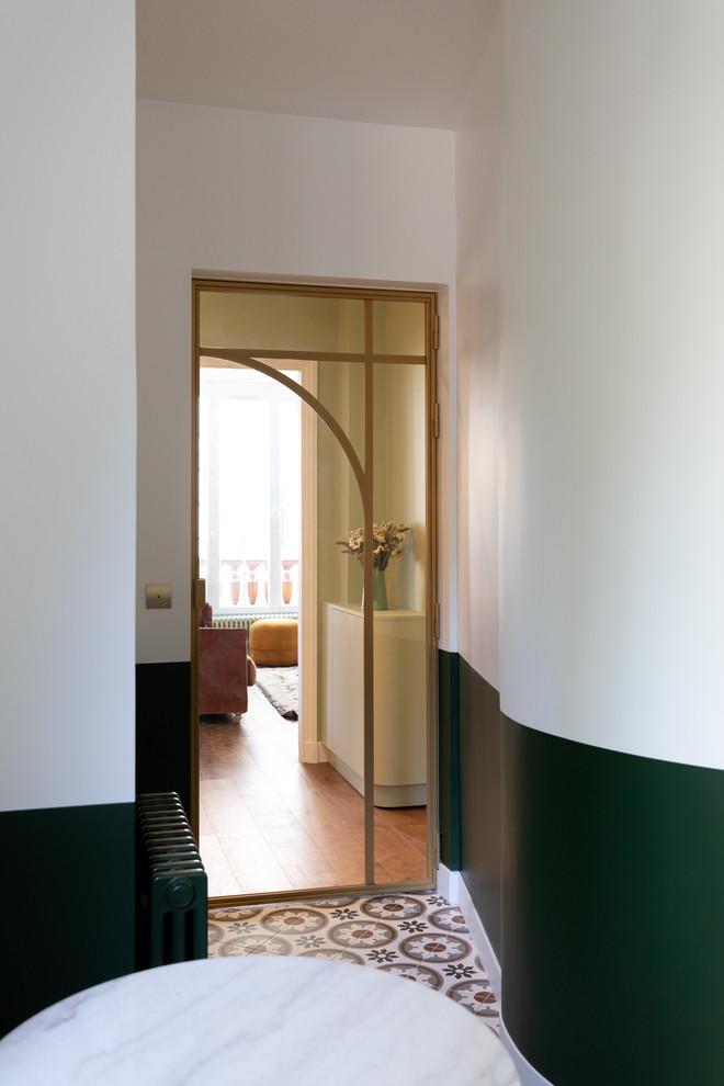 Exempel på ett avskilt, litet modernt brun brunt l-kök, med en enkel diskho, luckor med profilerade fronter, gröna skåp, träbänkskiva, vitt stänkskydd, stänkskydd i tunnelbanekakel, svarta vitvaror, cementgolv och flerfärgat golv
