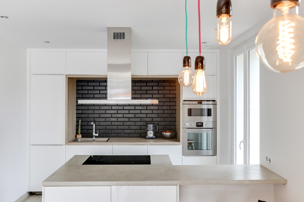 Inspiration for a medium sized contemporary galley kitchen/diner in Marseille with concrete worktops, black splashback, metro tiled splashback, stainless steel appliances, ceramic flooring, an island, a submerged sink, white cabinets and beige worktops.