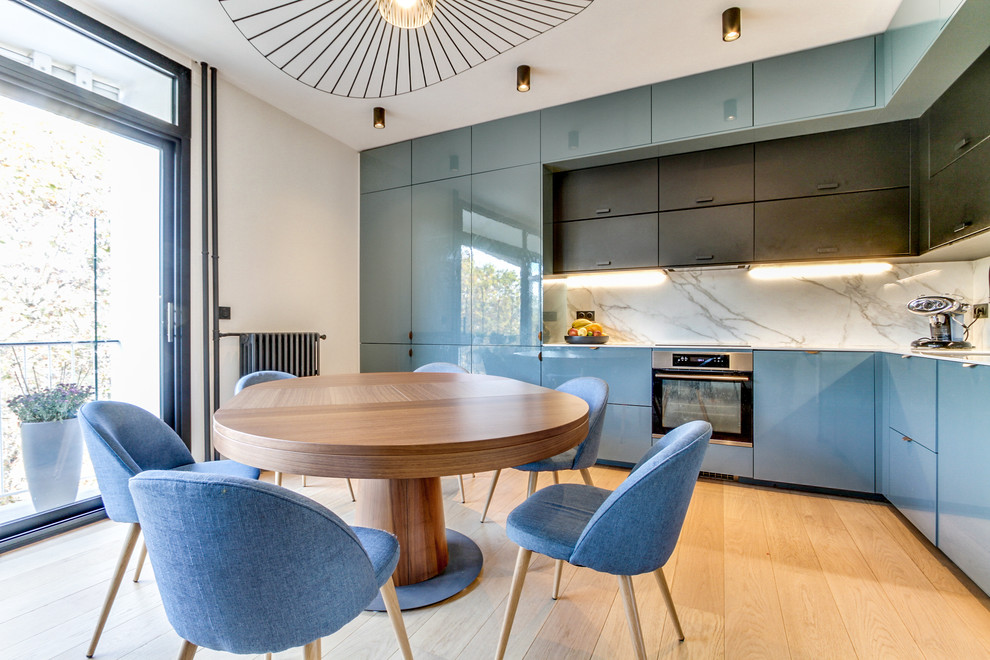 Ispirazione per una cucina minimal con ante lisce, ante blu, elettrodomestici in acciaio inossidabile, parquet chiaro e pavimento beige
