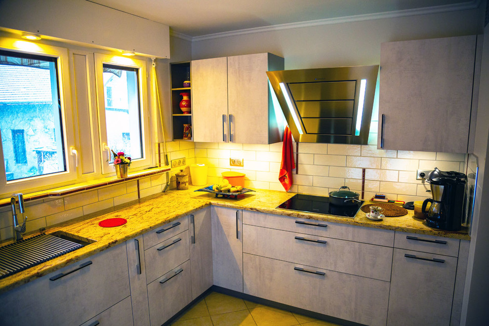 Foto di una cucina a L classica chiusa e di medie dimensioni con ante grigie, top in granito, elettrodomestici neri, nessuna isola, pavimento beige e top beige
