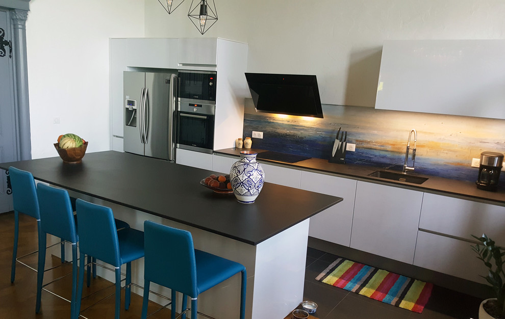 Medium sized modern single-wall kitchen/diner in Other with an integrated sink, multi-coloured splashback, black appliances, ceramic flooring, an island, black floors and black worktops.