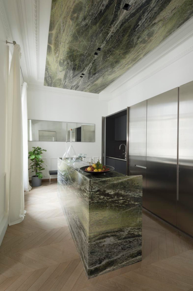 Cette image montre une cuisine design en inox avec un placard à porte plane, parquet clair, îlot, un sol beige et un plan de travail multicolore.