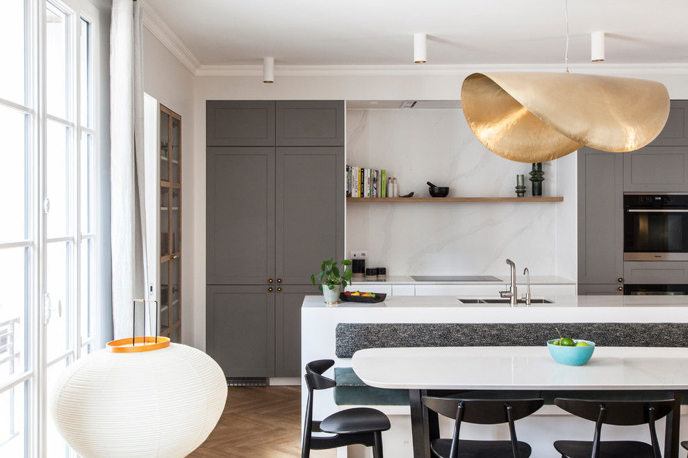 Foto di una cucina scandinava con lavello integrato, ante grigie, top in quarzite, paraspruzzi bianco, elettrodomestici da incasso, parquet chiaro e top bianco