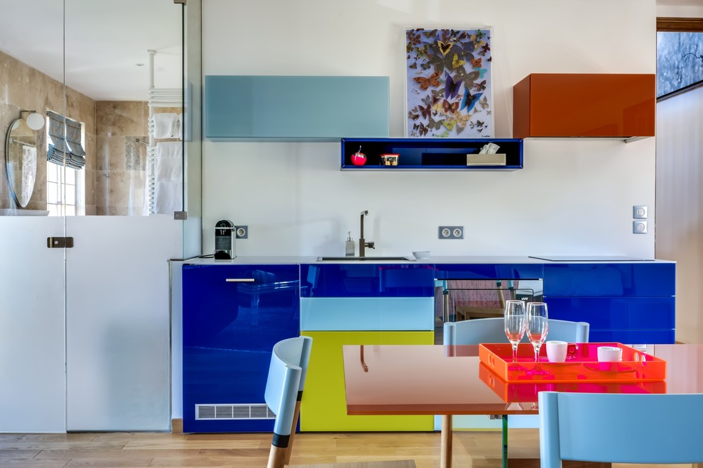 На фото: прямая кухня среднего размера в современном стиле с плоскими фасадами, светлым паркетным полом, обеденным столом и синими фасадами без острова с