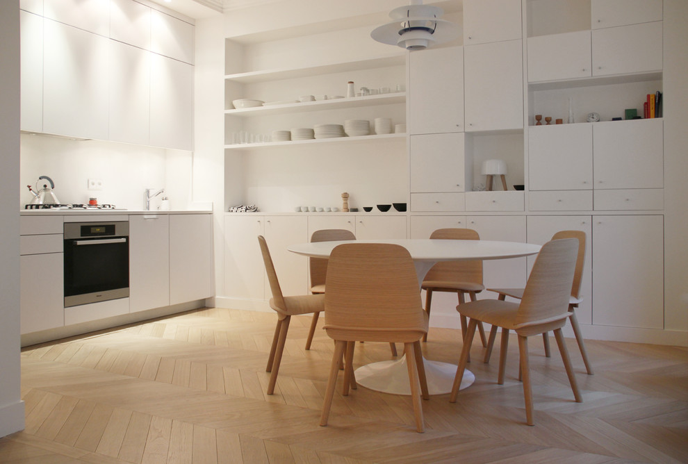 Modelo de cocina comedor lineal nórdica de tamaño medio sin isla con puertas de armario blancas y suelo de madera clara