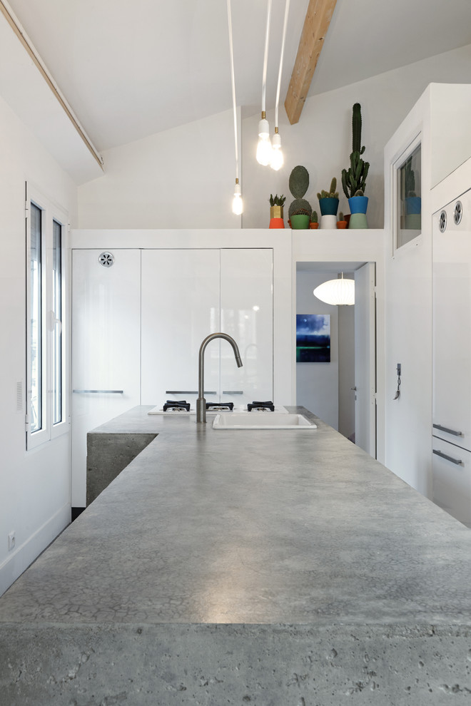 Exemple d'une grande cuisine tendance en L fermée avec un évier posé, des portes de placard blanches et un plan de travail en béton.