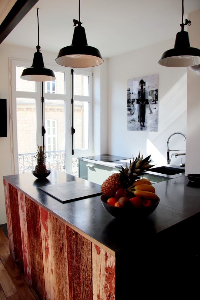 На фото: п-образная кухня среднего размера в стиле лофт с обеденным столом, монолитной мойкой, светлыми деревянными фасадами, столешницей из бетона и техникой под мебельный фасад с