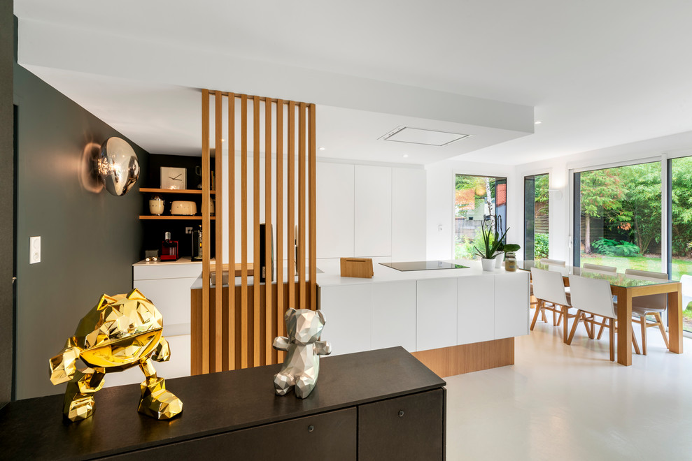 Photo of a large contemporary galley kitchen/diner in Nantes with a single-bowl sink, white cabinets, composite countertops, black appliances, concrete flooring, an island, white floors and white worktops.