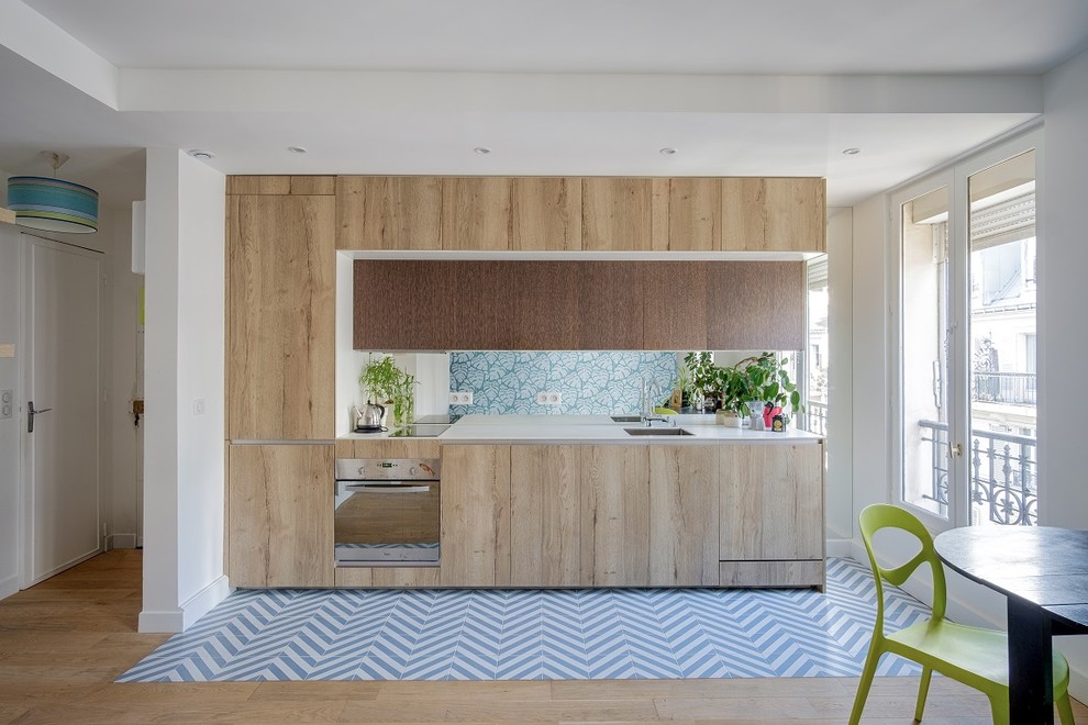 Idéer för ett litet modernt vit linjärt kök med öppen planlösning, med en integrerad diskho, skåp i mellenmörkt trä, bänkskiva i kvartsit, spegel som stänkskydd, rostfria vitvaror, cementgolv, blått golv, släta luckor och stänkskydd med metallisk yta