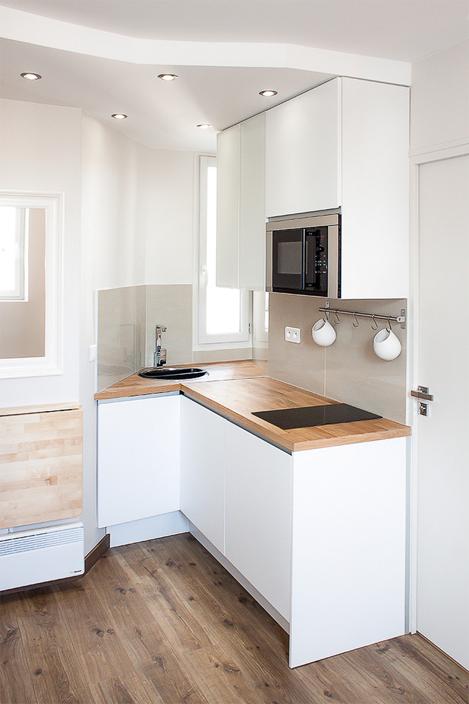 Imagen de cocina actual con fregadero integrado, encimera de madera, electrodomésticos de acero inoxidable, suelo de madera en tonos medios y suelo marrón