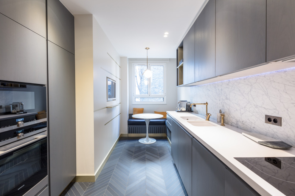Moderne Küche ohne Insel mit Doppelwaschbecken, flächenbündigen Schrankfronten, braunen Schränken, Küchenrückwand in Weiß, Rückwand aus Stein, grauem Boden und weißer Arbeitsplatte in Paris