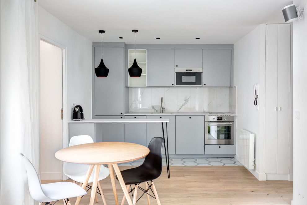 Design ideas for a small scandinavian single-wall open plan kitchen in Paris with a single-bowl sink, flat-panel cabinets, grey cabinets, laminate countertops, white splashback, ceramic splashback, stainless steel appliances, ceramic flooring, an island, white floors and white worktops.