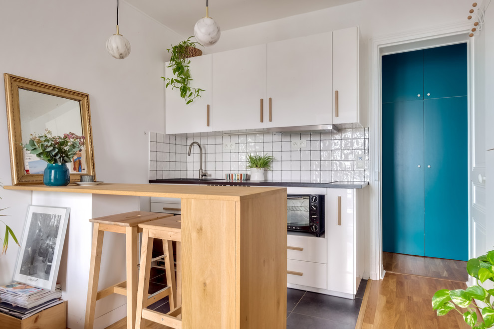 Idée de décoration pour une petite cuisine nordique avec un placard à porte plane, des portes de placard blanches, une crédence blanche, une péninsule, un sol gris et un plan de travail gris.