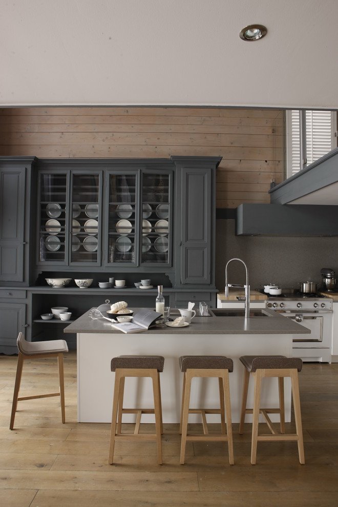 Diseño de cocina comedor contemporánea grande con puertas de armario grises, suelo de madera en tonos medios y una isla