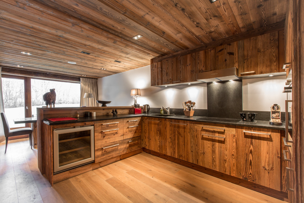 Große Rustikale Wohnküche in L-Form mit hellbraunen Holzschränken, Küchenrückwand in Schwarz, Rückwand aus Stein, Elektrogeräten mit Frontblende, braunem Holzboden und Halbinsel in Lyon