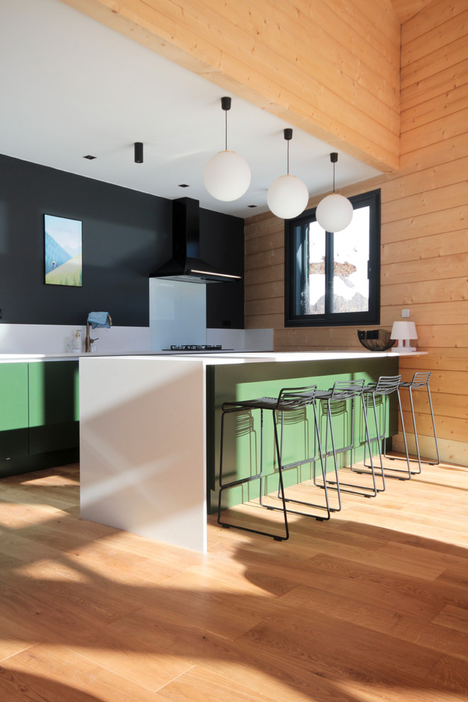 トゥールーズにある高級な中くらいなラスティックスタイルのおしゃれなキッチン (フラットパネル扉のキャビネット、緑のキャビネット、人工大理石カウンター、白いキッチンパネル、淡色無垢フローリング、白いキッチンカウンター、ガラス板のキッチンパネル) の写真