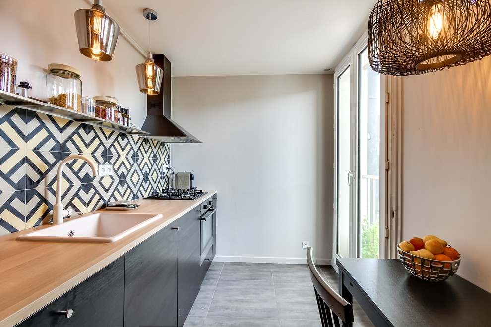 Inspiration for a mid-sized contemporary single-wall eat-in kitchen remodel in Paris with a drop-in sink, flat-panel cabinets, black cabinets, multicolored backsplash and no island