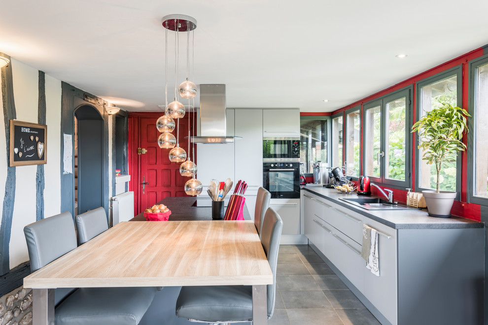 Stilmix Küche mit Rückwand-Fenster, schwarzen Elektrogeräten und grauem Boden in Le Havre