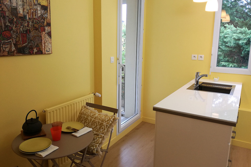 Foto di una cucina minimal con ante bianche, top in laminato, elettrodomestici neri, pavimento in vinile, pavimento beige e top bianco