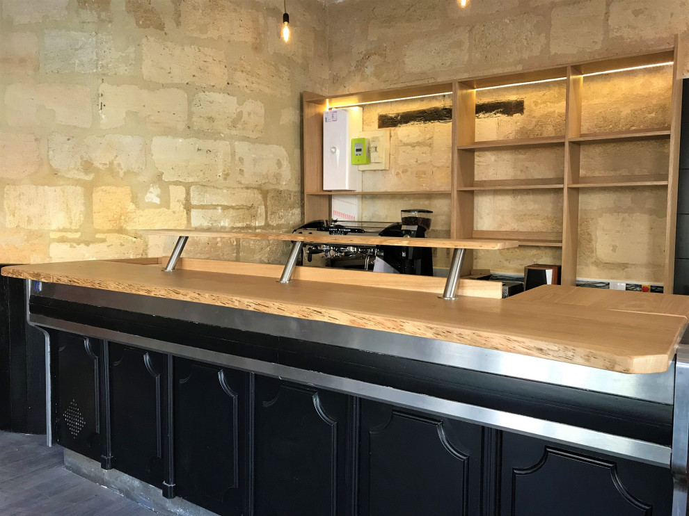 Inspiration for a medium sized rural u-shaped open plan kitchen in Bordeaux with a double-bowl sink, recessed-panel cabinets, black cabinets, wood worktops, beige splashback, limestone splashback, stainless steel appliances, laminate floors, an island and beige worktops.