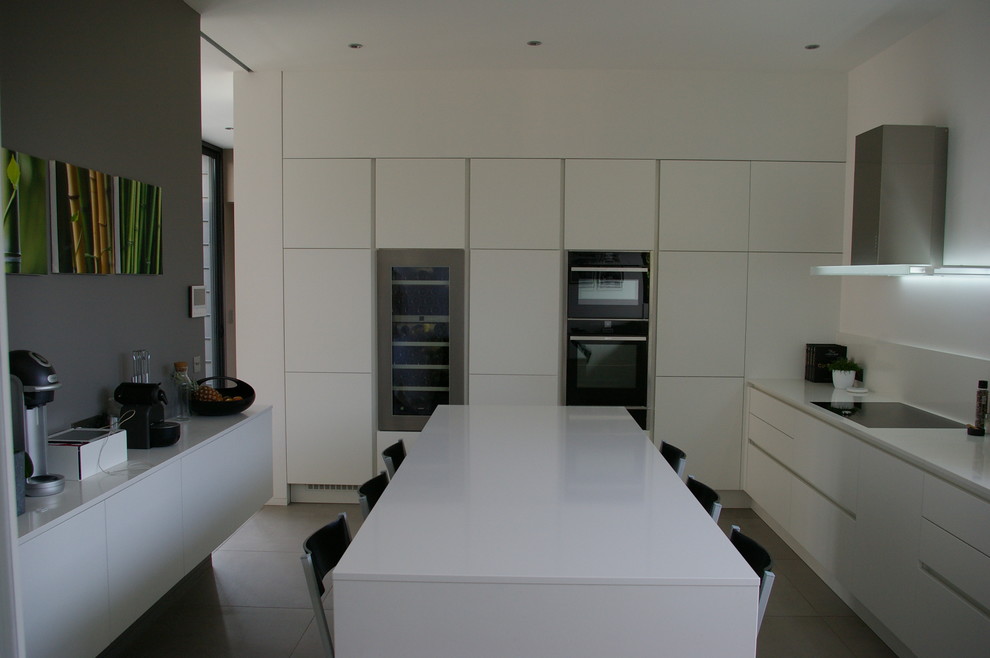 Exempel på ett avskilt, stort modernt parallellkök, med en undermonterad diskho, luckor med profilerade fronter, vita skåp, bänkskiva i kvarts, vitt stänkskydd, rostfria vitvaror, klinkergolv i keramik och en köksö