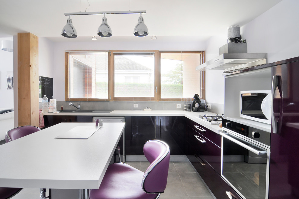 Свежая идея для дизайна: угловая кухня среднего размера в современном стиле с двойной мойкой, плоскими фасадами, серым фартуком, островом и обеденным столом - отличное фото интерьера