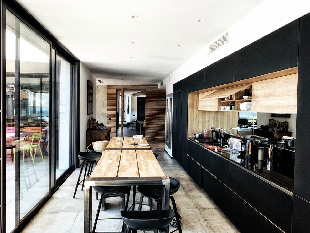 Design ideas for a large nautical single-wall open plan kitchen in Marseille with a submerged sink, flat-panel cabinets, black cabinets, beige splashback, wood splashback, integrated appliances, concrete flooring, no island, grey floors and black worktops.
