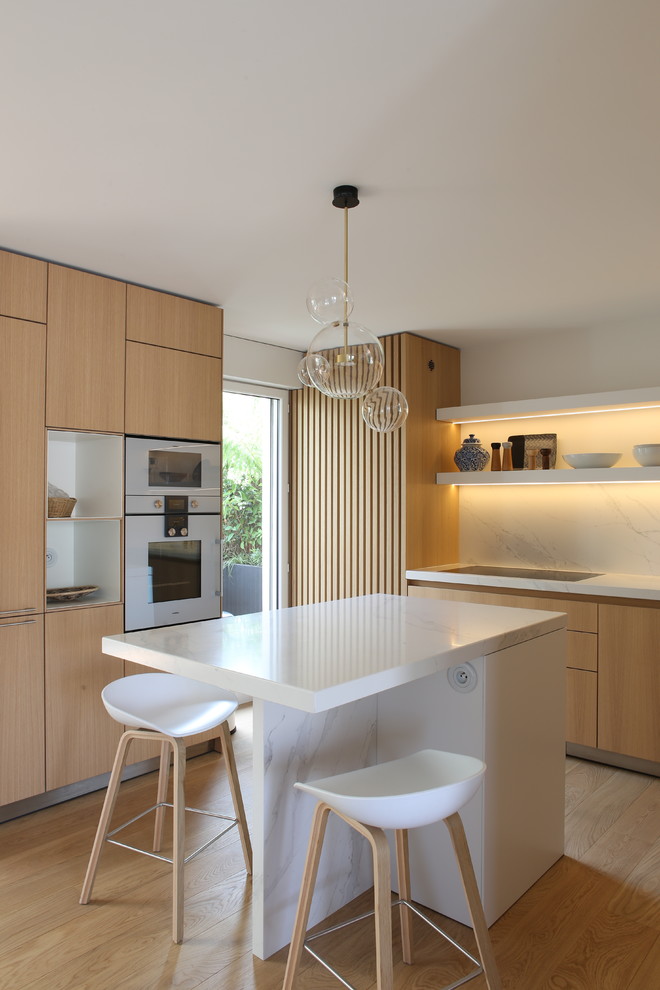 Inspiration for a medium sized contemporary kitchen in Paris with marble worktops, light hardwood flooring, an island, beige floors, white worktops, flat-panel cabinets, light wood cabinets, white splashback and marble splashback.