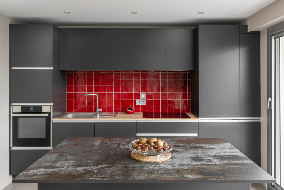 Small contemporary galley open plan kitchen in Nantes with a built-in sink, beaded cabinets, grey cabinets, composite countertops, red splashback, ceramic splashback, stainless steel appliances, concrete flooring, an island and yellow worktops.