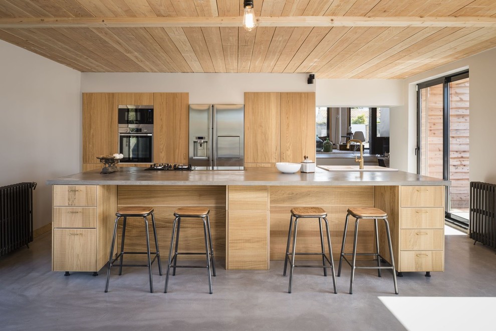 Idéer för funkis grått kök, med en dubbel diskho, släta luckor, skåp i mellenmörkt trä, rostfria vitvaror, betonggolv, en köksö och grått golv