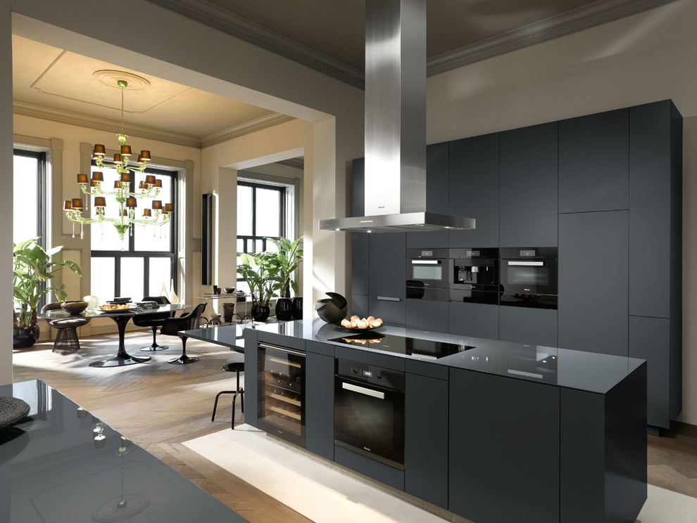 Offene, Zweizeilige, Große Moderne Küche mit schwarzen Schränken, schwarzen Elektrogeräten, braunem Holzboden und Kücheninsel in Oxfordshire