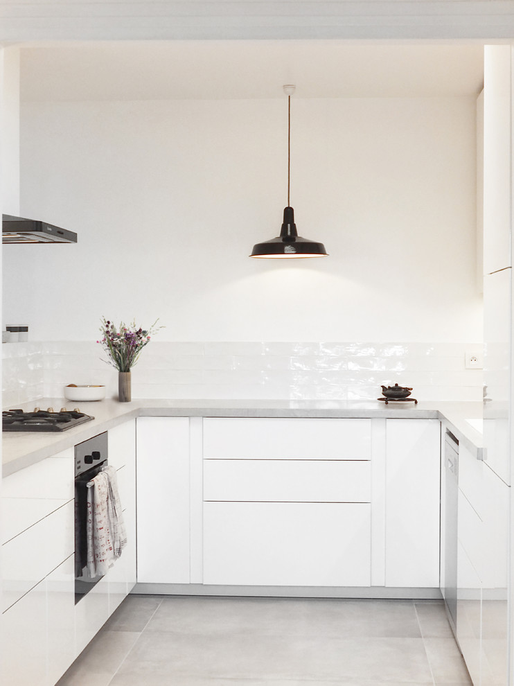 Foto på ett stort funkis grå kök, med vita skåp, vitt stänkskydd, svarta vitvaror, en undermonterad diskho, bänkskiva i betong, stänkskydd i keramik, cementgolv och grått golv