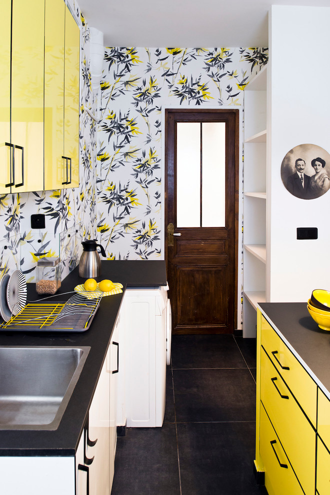Idée de décoration pour une cuisine parallèle et bicolore bohème avec un évier posé, un placard à porte plane, des portes de placard jaunes, un sol noir, plan de travail noir et papier peint.