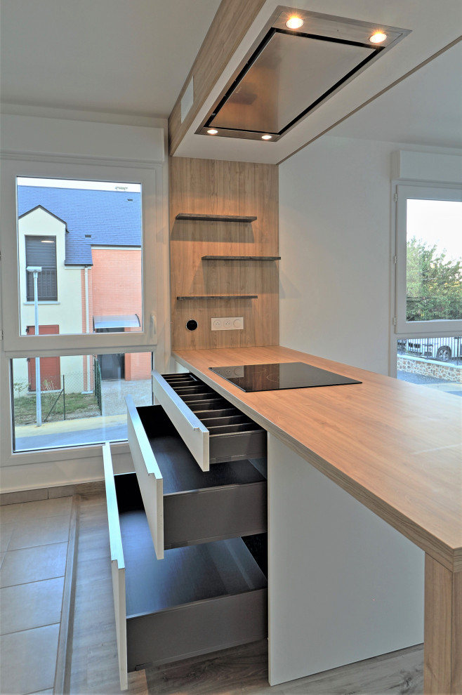 This is an example of a medium sized contemporary u-shaped open plan kitchen in Other with a submerged sink, flat-panel cabinets, white cabinets, wood worktops, grey splashback, slate splashback, stainless steel appliances, laminate floors, an island, brown floors and brown worktops.
