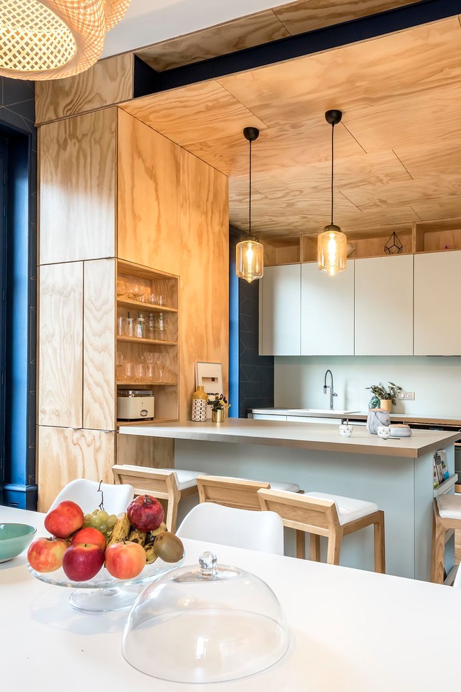 Mittelgroße Moderne Wohnküche mit Kassettenfronten, grünen Schränken, Laminat-Arbeitsplatte, Küchenrückwand in Grün, hellem Holzboden, Kücheninsel und grüner Arbeitsplatte in Clermont-Ferrand